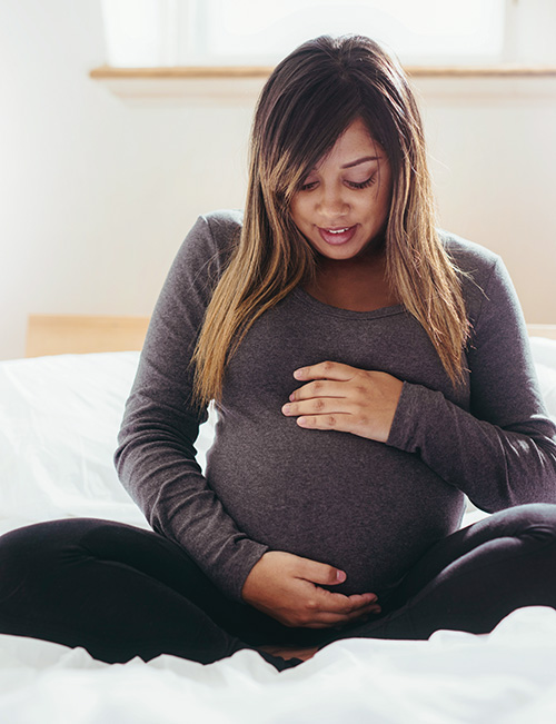 Pregnant woman gently holding her baby bump